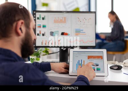 Businessman in wheelchair analyzing financial graph using tablet computer working at management statistics in startup company office. Handicapped disabled manager planning digital strategy Stock Photo