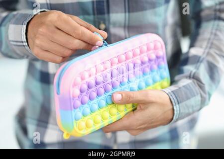 Woman is unbuttoning bright pops it pencil case Stock Photo