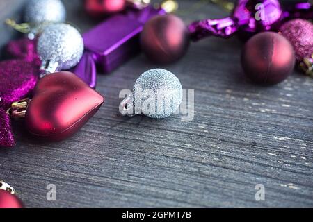 Close up of tiny silver sparkling Christmas ball. New year toys, hearts and balls on wooden grey surface. Flat layer composition for winter holiday Stock Photo