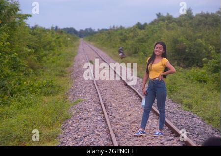 Asian girl wearing a stylish poses poses in the train station, the  background is the sun is falling. Stock Photo | Adobe Stock