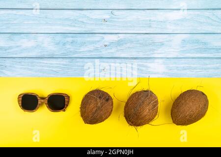 coconuts and sunglasses in lies on a blue wooden background and a yellow background. Stock Photo