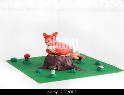 Plasticine world - small sweet red fox lying on a stump Stock Photo