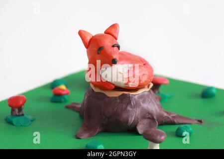 Plasticine world - small sweet red fox lying on a stump Stock Photo