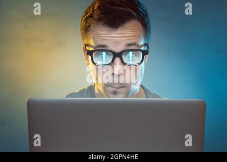 Man in front of a computer with exclamation points reflecting in his glasses Stock Photo