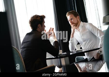 Colleagues and friends. Two cheerful businessmen drinking coffee and talking to each other Stock Photo
