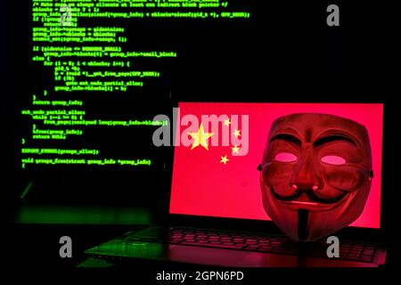 Chinese anonymous hackers with vendetta mask. China flag and programming code in background Stock Photo
