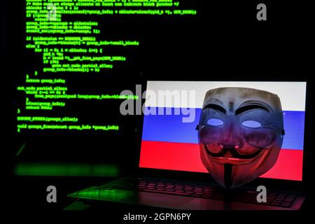 Russian anonymous hackers with vendetta mask. Russian flag and programming code in background Stock Photo
