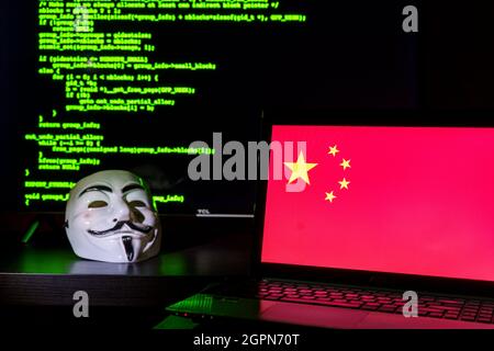 Chinese anonymous hackers with vendetta mask. China flag and programming code in background Stock Photo