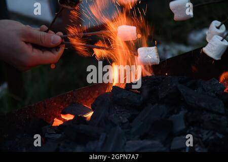 Roasting and cooking marshmallow on a fire at the evening. Close up. Stock Photo