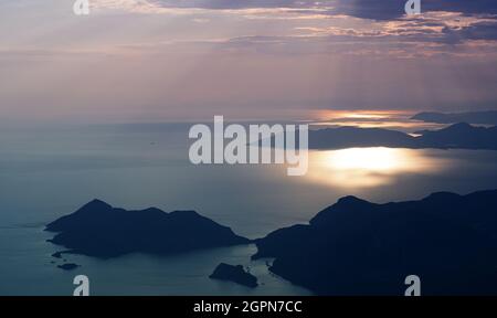 beautiful aerial panorama from the Babadag peak of high mountains rising up over the Mediterranean sea at sunset near Oludeniz Blue Lagoon coast in Tu Stock Photo
