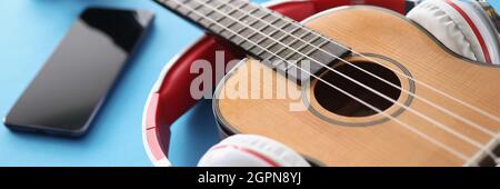 Wooden guitar headphones. and smartphone on blue background Stock Photo