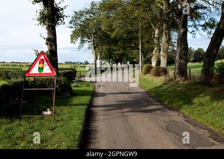 Temporary traffic lights warning sign on a country lane Stock Photo