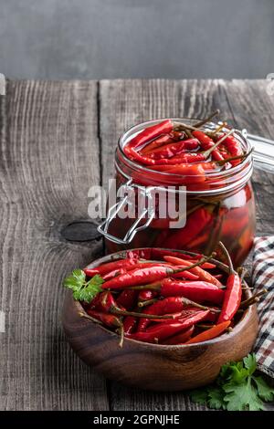 red spicy  marinated pepper in wooden bowl on the rustic table Stock Photo