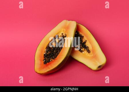 Halves of ripe papaya on pink background Stock Photo