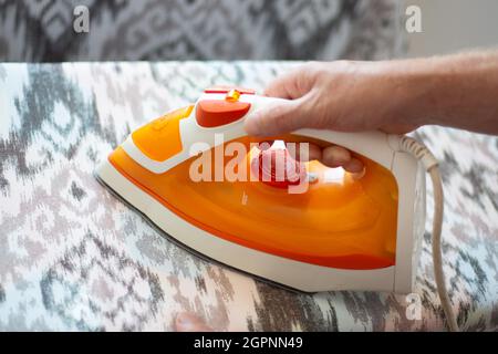 A man ironing linen with an electric iron on an ironing board. Help around the house. Stock Photo