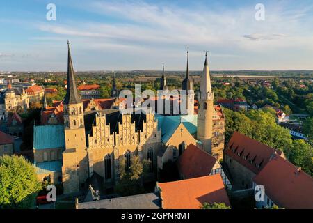 Merseburg, Germany. 30th Sep, 2021. The morning sun shines down on Merseburg Cathedral. A three-day festival in Merseburg from 1 to 3 October commemorates the consecration of the cathedral 1000 years ago. One of the highlights of the program under the motto 'Consecrated for Eternity' is a procession during which the cathedral will ceremoniously receive a new bell. According to tradition, Merseburg Cathedral was consecrated on October 1, 1021 in the presence of Emperor Heinrich II and his wife Kunigunde. (Aerial view with drone) Credit: Jan Woitas/dpa-Zentralbild/dpa/Alamy Live News Stock Photo