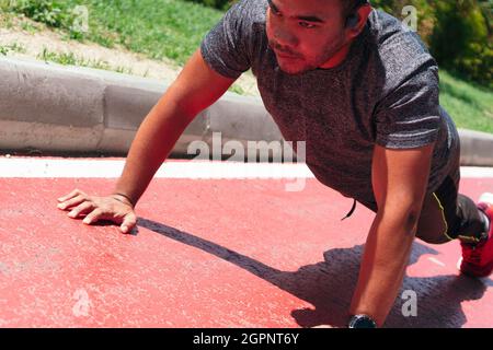 Hispanic Man doing pushups in the park on the athletic track. Stock Photo