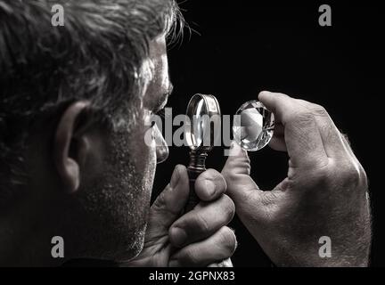 Large gemstone in jeweler's hand close up. Gem identifying and evaluating process. Stock Photo