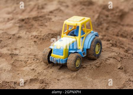 Children's toy tractor on the sandbox.A forgotten toy Stock Photo