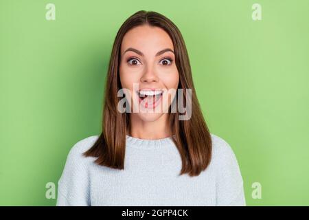 Photo of impressed young brunette lady wear blue sweater isolated on green color background Stock Photo