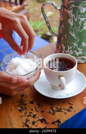 Of pouring sugar in hot tea on a wooden table Stock Photo