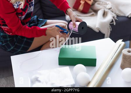 Close-up of a woman cutting gift wrapping paper with sciss…