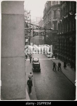 Martins Bank, Lombard Street, City and County of the City of London, Greater London Authority, 1950-1953. Looking east along Great George Street towards Big Ben and Parliament Square, with pedestrians on the pavement in the foreground. The sign of the grasshopper was the crest of the Gresham family, and was used to distinguish the house of Thomas Gresham in Lombard Street in the 16th century. Gresham was a financier to Edward VI, Mary I and Elizabeth I, and founder of the Royal Exchange. The sign bears Gresham's initials and the date 1563; it is believed he traded at the site from this date. T Stock Photo