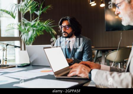Italy, Businessmen using laptops in creative studio Stock Photo