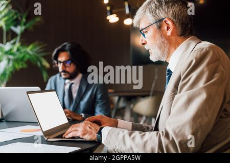 Italy, Businessmen using laptops in creative studio Stock Photo