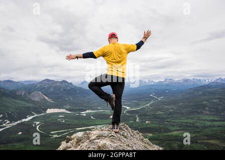 USA, Alaska, Hiker standing on one leg on mountain top in Denali National Park Stock Photo