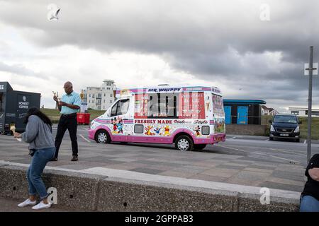 A mobile Ice Cream and drinks van with customers on the promenade at Crosby beach, north of Liverpool City in Merseyside, England Stock Photo