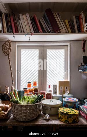 Cookery books and marmalade with etched glass window in larder of Suffolk cottage. Stock Photo