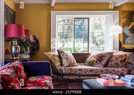 Ercol daybed with mix of bold colours and fabrics in Suffolk living room. Stock Photo