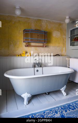 Wall mounted cabinet and rubber ducks with freestanding bath in Suffolk cottage. Stock Photo