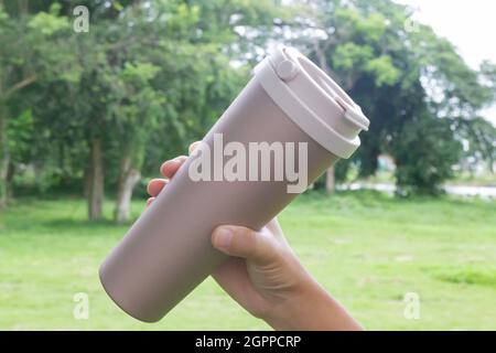 Hand on coffee stainles steel thermo cup, stock photo Stock Photo