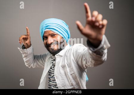 Young sikh man Balle balle Gurmukhi style indian cultural dancing on studio background - concept of happiness and relaxation Stock Photo