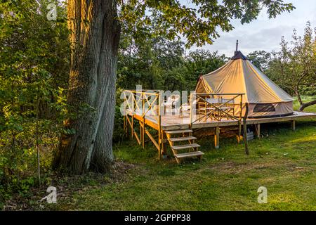 Glamping in the garden of the Villa Skovly (Beths Hus) in Hesselager, Denmark. The spacious tent with a double bed is located on a wooden terrace in the orchard of the villa. The property includes a private beach.