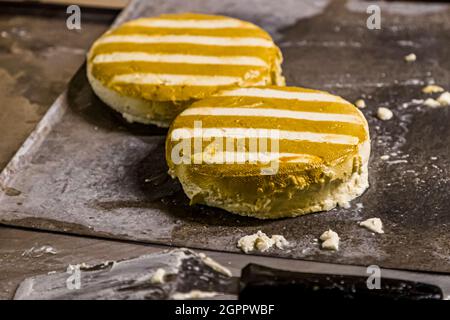 Production of the unique smoked cheese in the Gundestrup Dairy and Brewery (Gundestrup Mejeri og Bryghus). After 20 seconds in the dense smoke from straw  the cheese wheels are striped Gundestrup, Svendborg, Denmark Stock Photo