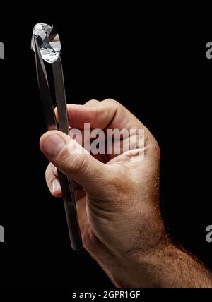 Large gemstone in jeweler's hand close up. Gem identifying and evaluating process. Stock Photo