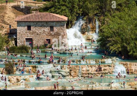 Saturnia, Grosseto, Italy, july 2021. Large group of people bathing in the natural thermal waters in Saturnia thermal waterfalls Stock Photo