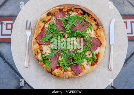 Sliced Pizza with Parma ham and oragula on a white plate.Snack at St Regis hotel, Nursultan Kazakhstan Stock Photo