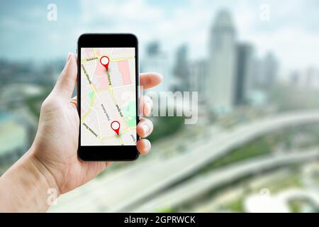 Man hand holding smartphone with GPS Map to Route Destination network connection. Location Street Map with GPS Icons Navigation. Stock Photo