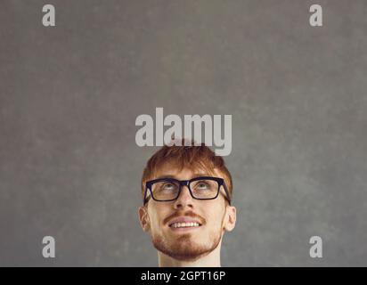 Close up of the head of a man who is dreamily and enchanted looking up on a gray background. Stock Photo