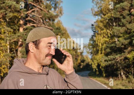 Senior Muslim asian man talking on phone and smiling Stock Photo