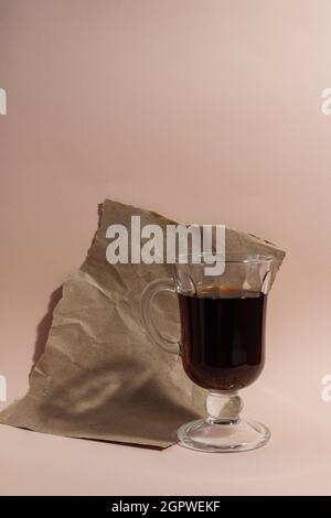 glass of pomegranate juice with torn and wrapping paper against pale pink background Stock Photo
