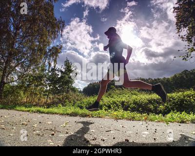 Jogging Tall Sports Man In Trees Shadows With Sun Light Behind Him.  While Wearing