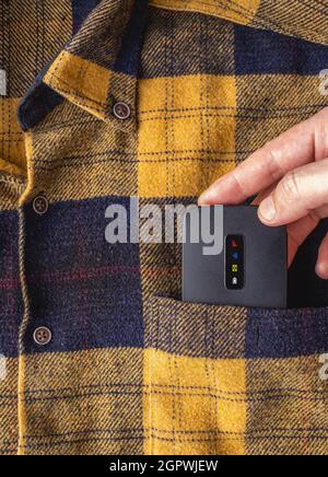 Mobile Pocket wifi router. Hand putting mobile wifi modem in shirt pocket. Stock Photo