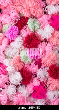 knitted wool flowers abstract, colorful woven yarn background texture, backdrop or wallpaper closeup Stock Photo