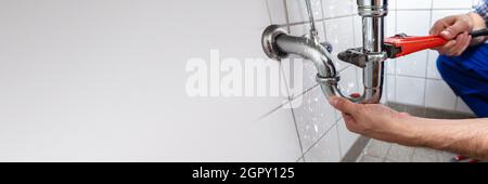 Plumber Worker Fixing Bathroom Pipe. Plumbing Maintenance Stock Photo