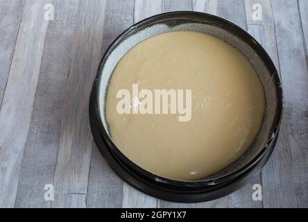 Step by step the process of making sour cream pie dough. Ready raw dough in a prepared baking dish. Baking concept. Stock Photo